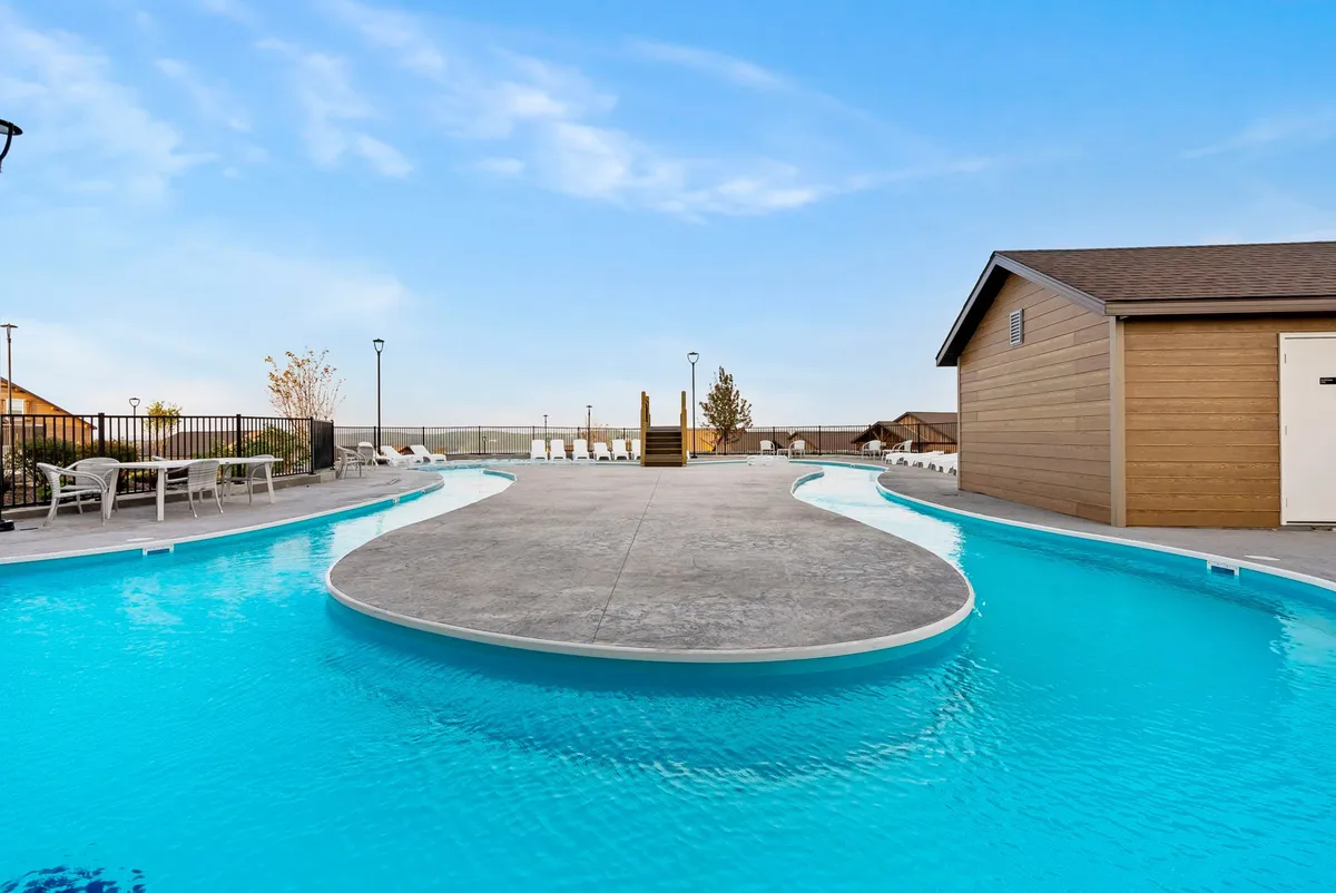 This exterior image highlights a spacious swimming pool with a surrounding deck area and lush landscape. The setting is open and inviting, perfect for both relaxation and social gatherings. The pool area seamlessly blends the natural surroundings with the comforts of a private retreat.