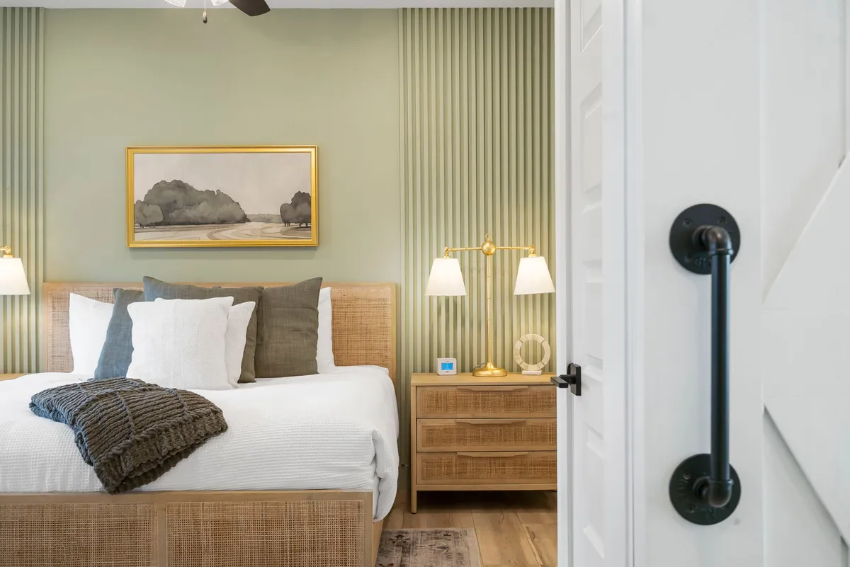 A serene king bedroom with decorative pillows, framed artwork, and soft lighting from table lamps. The tranquil setting offers a sense of privacy and luxury, ideal for couples or grandparents seeking restful nights.