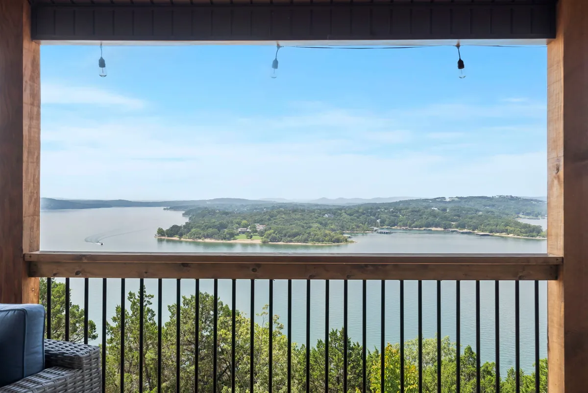 A serene view from a wooden deck or railing, overlooking the vast expanse of Table Rock Lake and distant hills, perfect for unwinding and soaking in the scenery. The tranquil mood ties in evening stargazing or early morning relaxation.